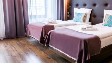 A hotel room with two beds, a dark headboard, and a window with curtains.