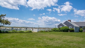A grassy area with a house and a white fence. - East Harbour Motel and Cottages (North Truro)