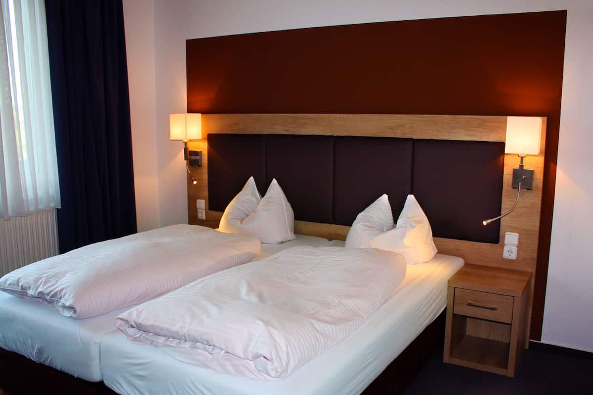 A double bed with two pillows and a nightstand with a lamp.