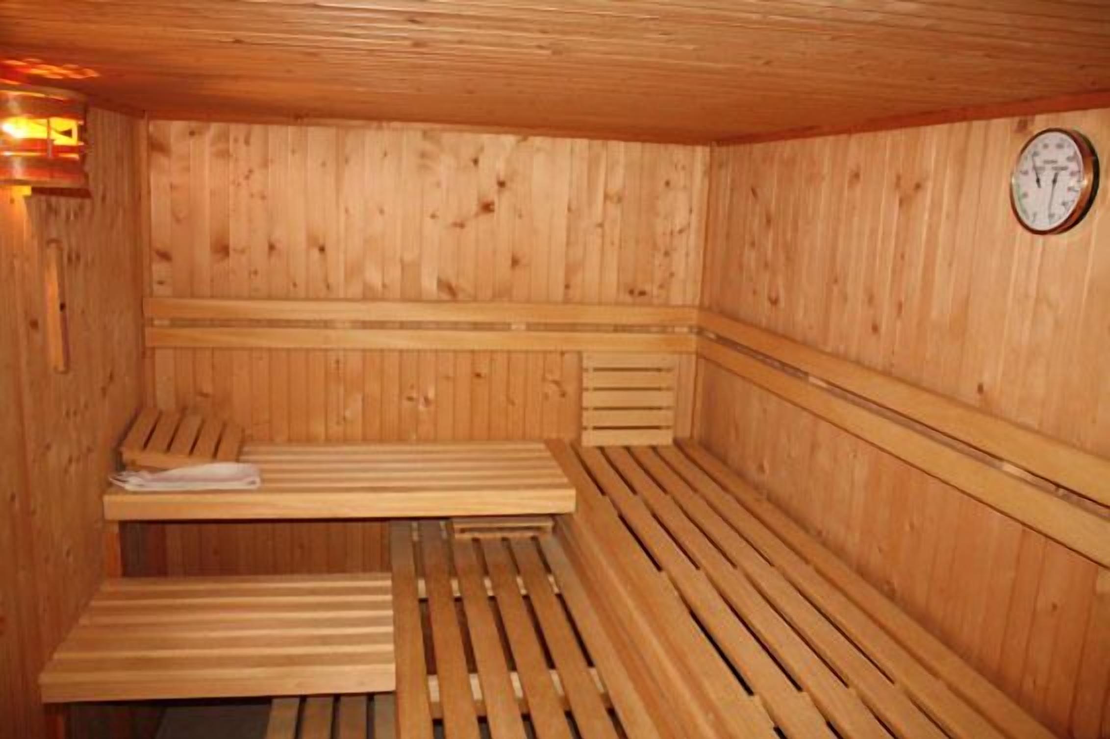 A wooden sauna with benches and a wall-mounted clock.