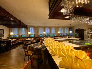 Un interior de restaurante con mobiliario de madera, una barra larga y varias ventanas.