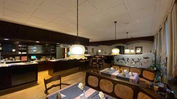 Un restaurante con zona de bar, suelo de madera y techo alto con vigas a la vista.