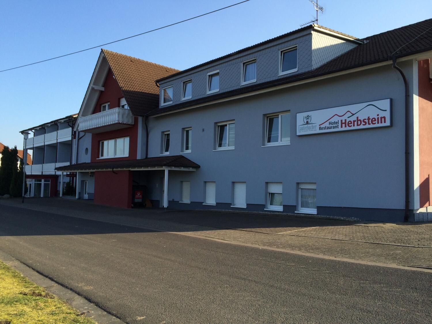 Ein zweistöckiges Gebäude mit einem Schild für 'Hotel Herbstein' und 'Lauerbacher Restaurant'.