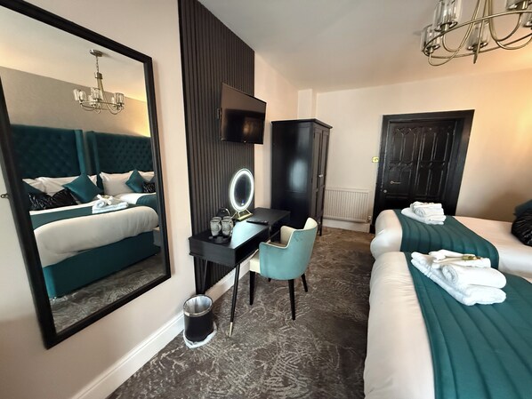 A hotel room with a large bed, a desk with a mirror, a chair, and a television.