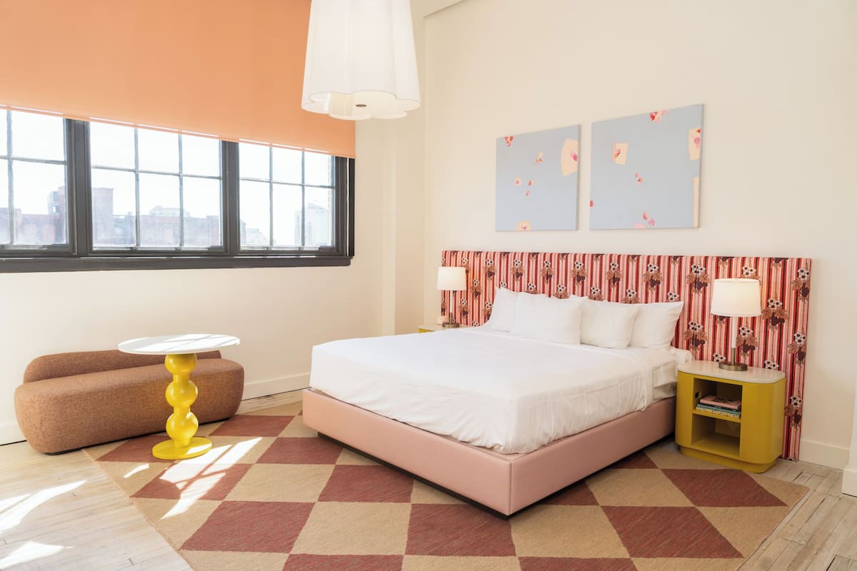 A bedroom with a bed, a sofa, a small table, and a nightstand.