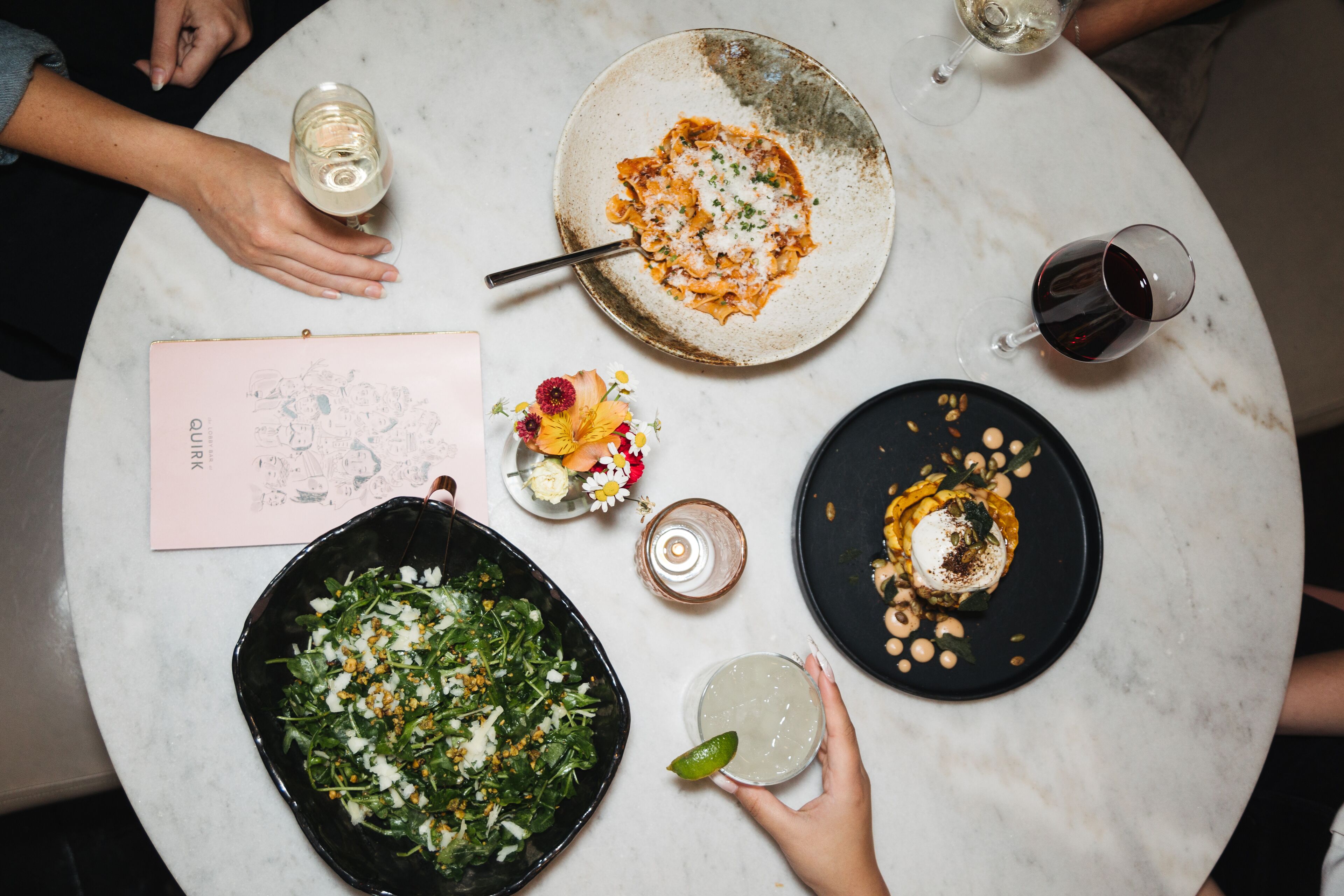 A round table with various dishes, drinks, and a menu.