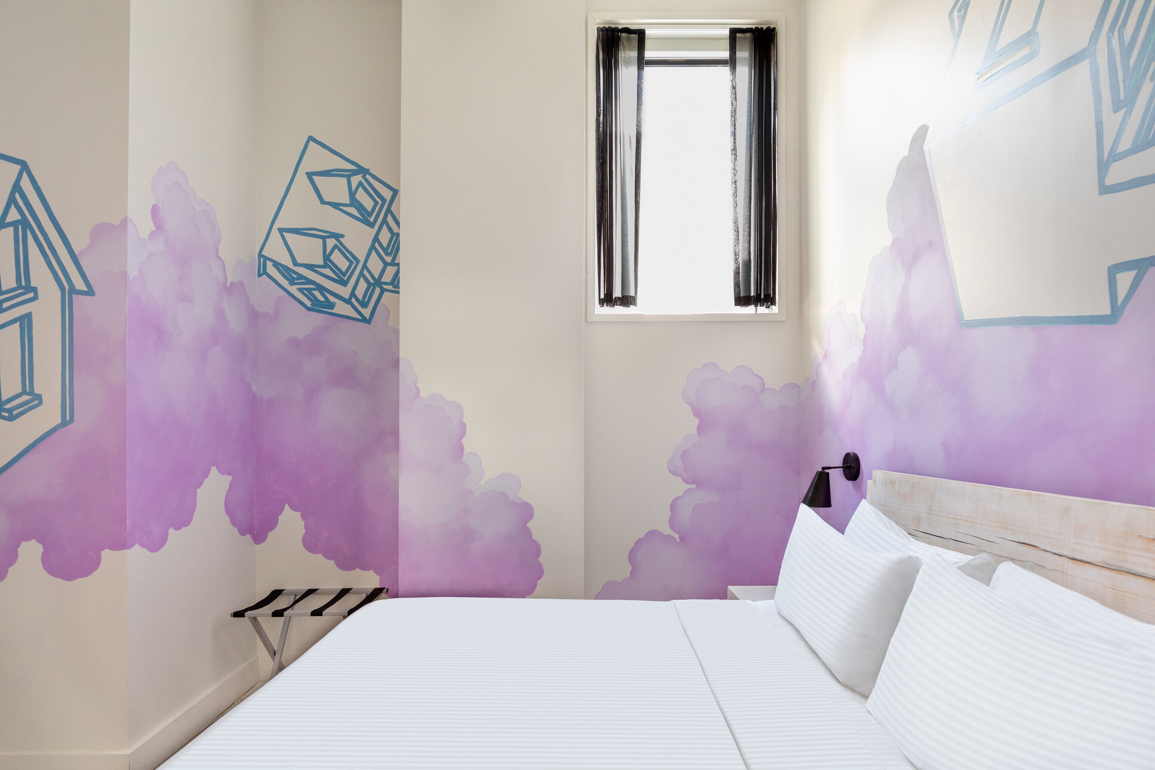 Un dormitorio con cama, ventana y paredes decoradas con patrones geométricos.