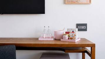 A wooden desk with a pink Igloo refrigerator, a blackboard, and a framed artwork on the wall.