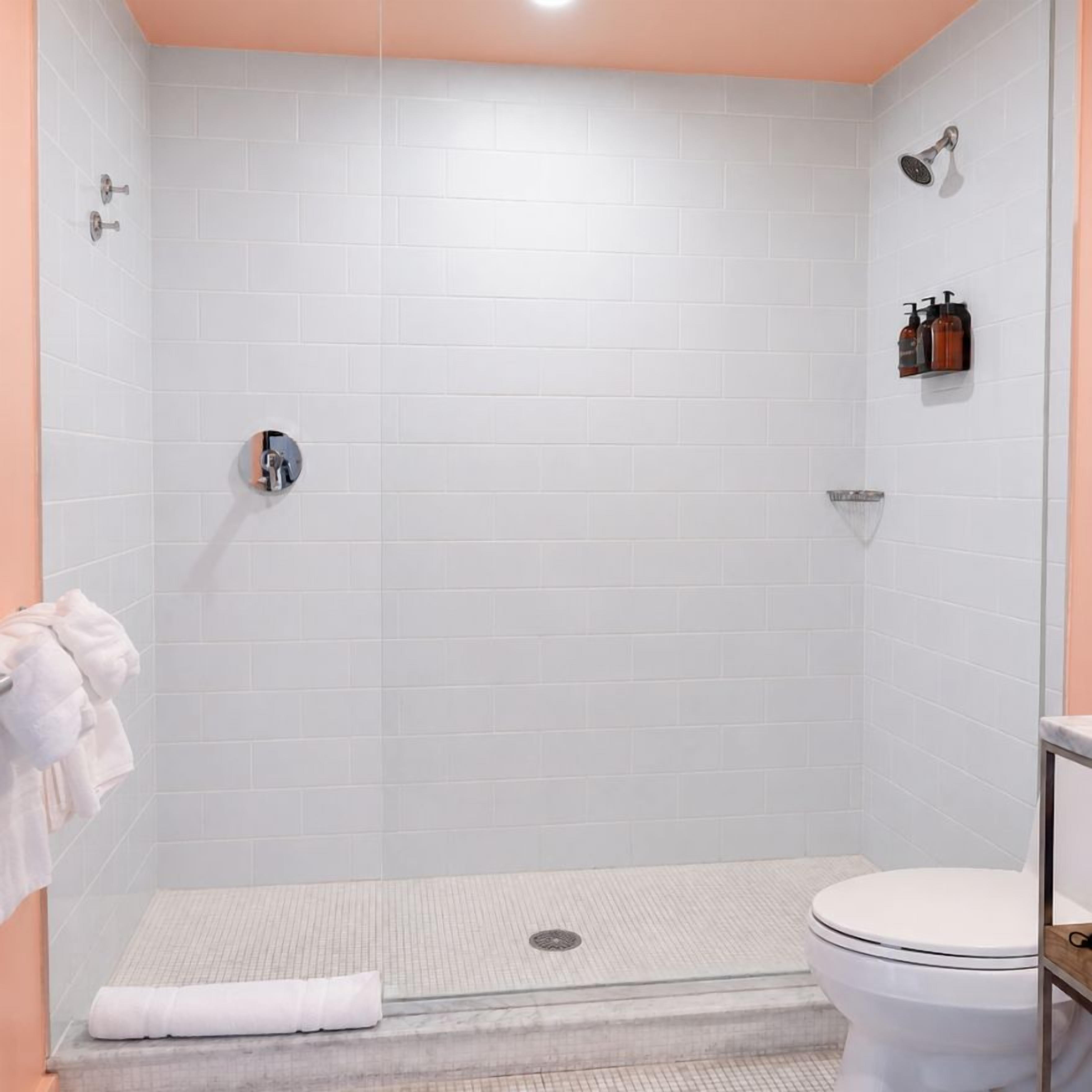 A bathroom with a shower, toilet, and a towel rack.