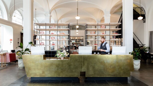 A lobby with a reception desk, bookshelves, and a staircase. - Quirk Hotel Richmond (Richmond)