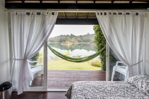 Un dormitorio con cama, vista a un lago y una hamaca.