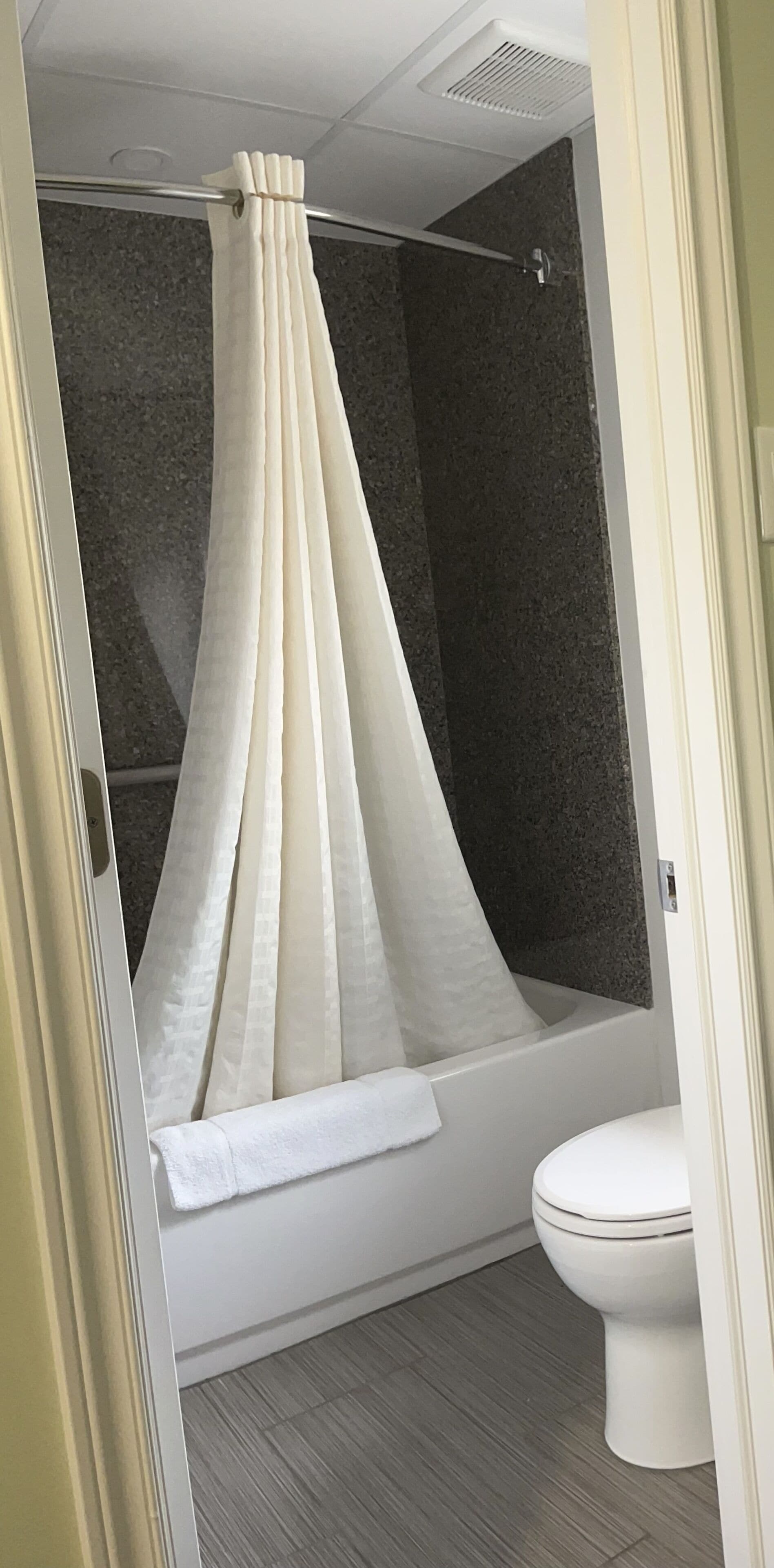 Un baño con cortina de ducha, bañera y retrete.