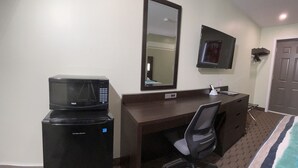 A hotel room with a bed, a desk with a chair, a microwave, a small refrigerator, a mirror, and a television mounted on the wall. - Budget Inn Port Hope (Port Hope)