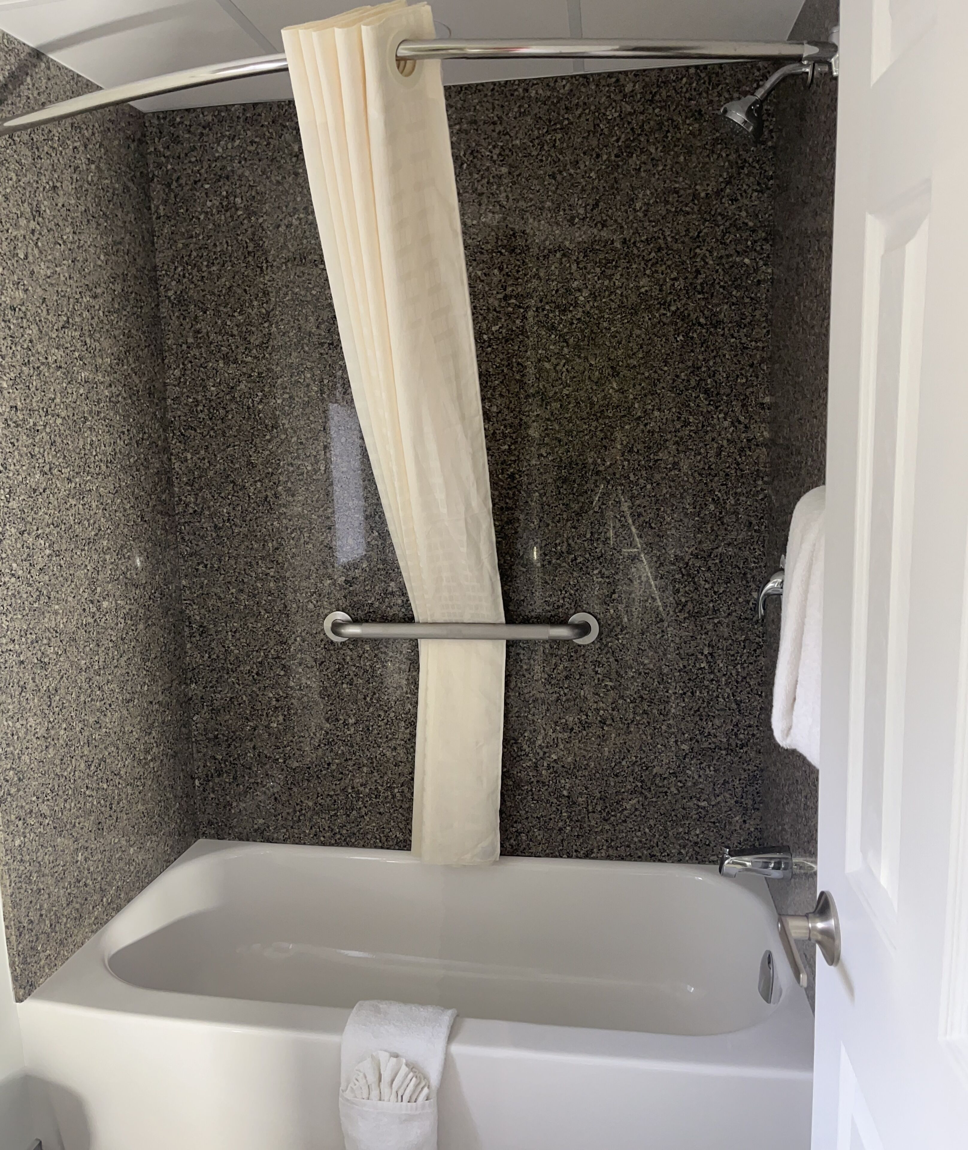 A bathroom with a bathtub, a shower curtain, and a towel rack.