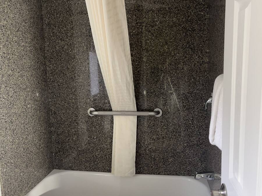 A bathroom with a bathtub, a shower curtain, and a towel rack.