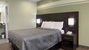 A hotel room with a large bed, a bedside table with a phone, and a nightstand with a lamp. - Budget Inn Port Hope (Port Hope)