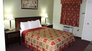 Habitación de hotel con una cama grande, dos mesitas de noche con lámparas, un cuadro en la pared, una ventana con cortinas y un termostato en la pared.