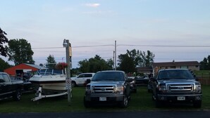 A parking lot with two trucks, a boat, and a red building in the background. - Budget Inn Port Hope (Port Hope)