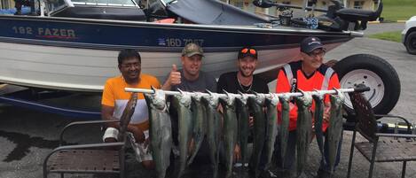 A boat named '192 FAZER' with four people holding fish.