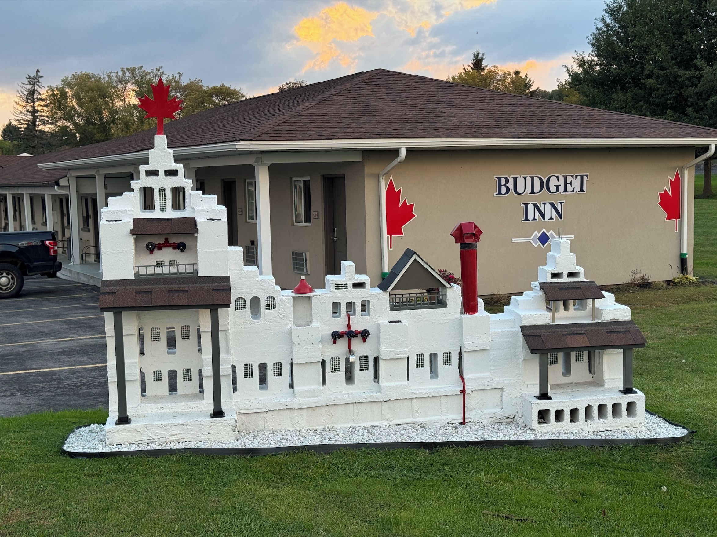Une maquette représentant un édifice ressemblant à un château, placée devant un bâtiment portant l’inscription « BUDGET INN ».