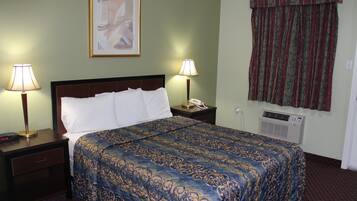Habitación de hotel con una cama bien hecha, dos lámparas de noche, una mesita de noche con teléfono y un aire acondicionado de pared.