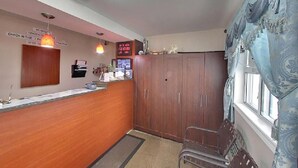 A reception area with a wooden counter, a digital display, and a set of wooden cabinets. - Budget Inn Port Hope (Port Hope)