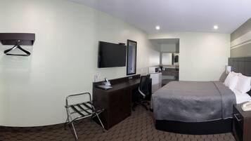 A hotel room with a bed, a desk, a chair, a TV, and a mirror.