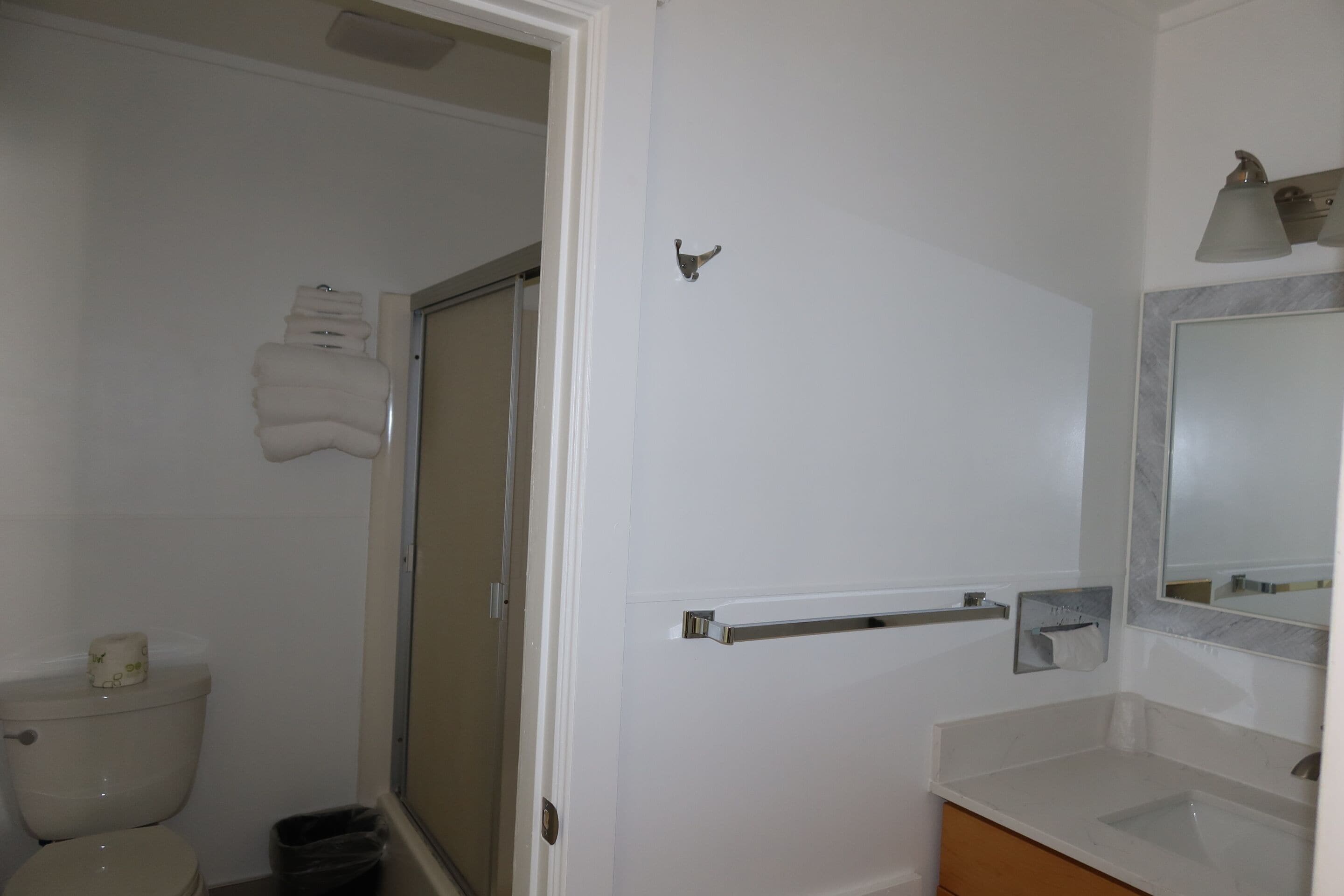 Une salle de bain équipée de toilettes, d’un lavabo, d’un miroir et d’un porte-serviettes.