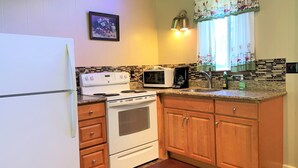 A kitchen with a white refrigerator, stove, microwave, and wooden cabinets. - Mountain View Lodge (Packwood)