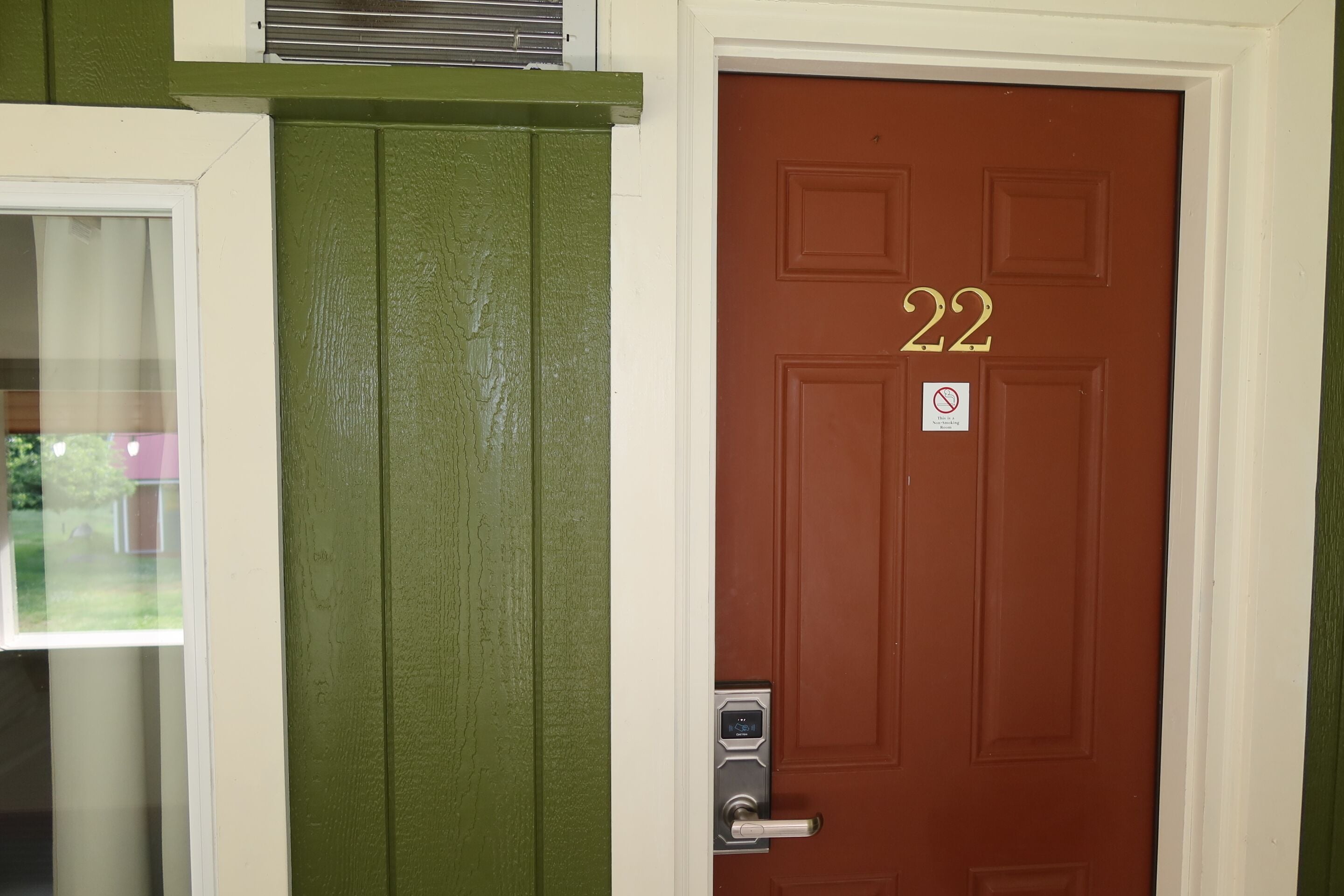A brown door with the number 22, a doorbell, and a no smoking sign.