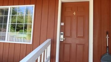 A brown door with the number 4, a window with a view of trees, and a white railing.