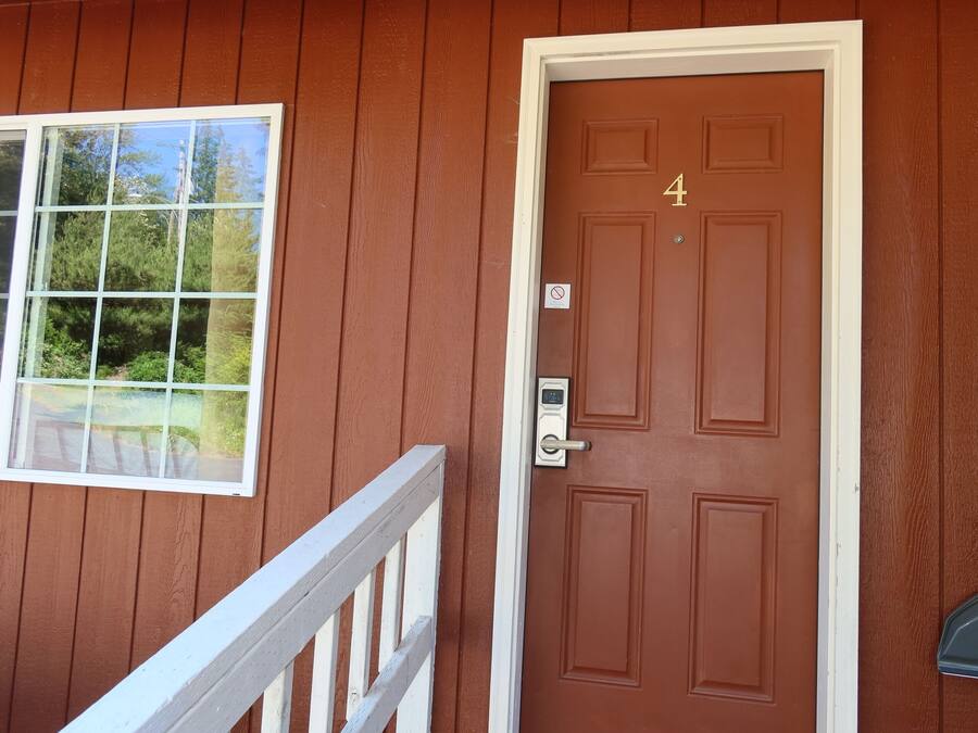A brown door with the number 4, a window with a view of trees, and a white railing.