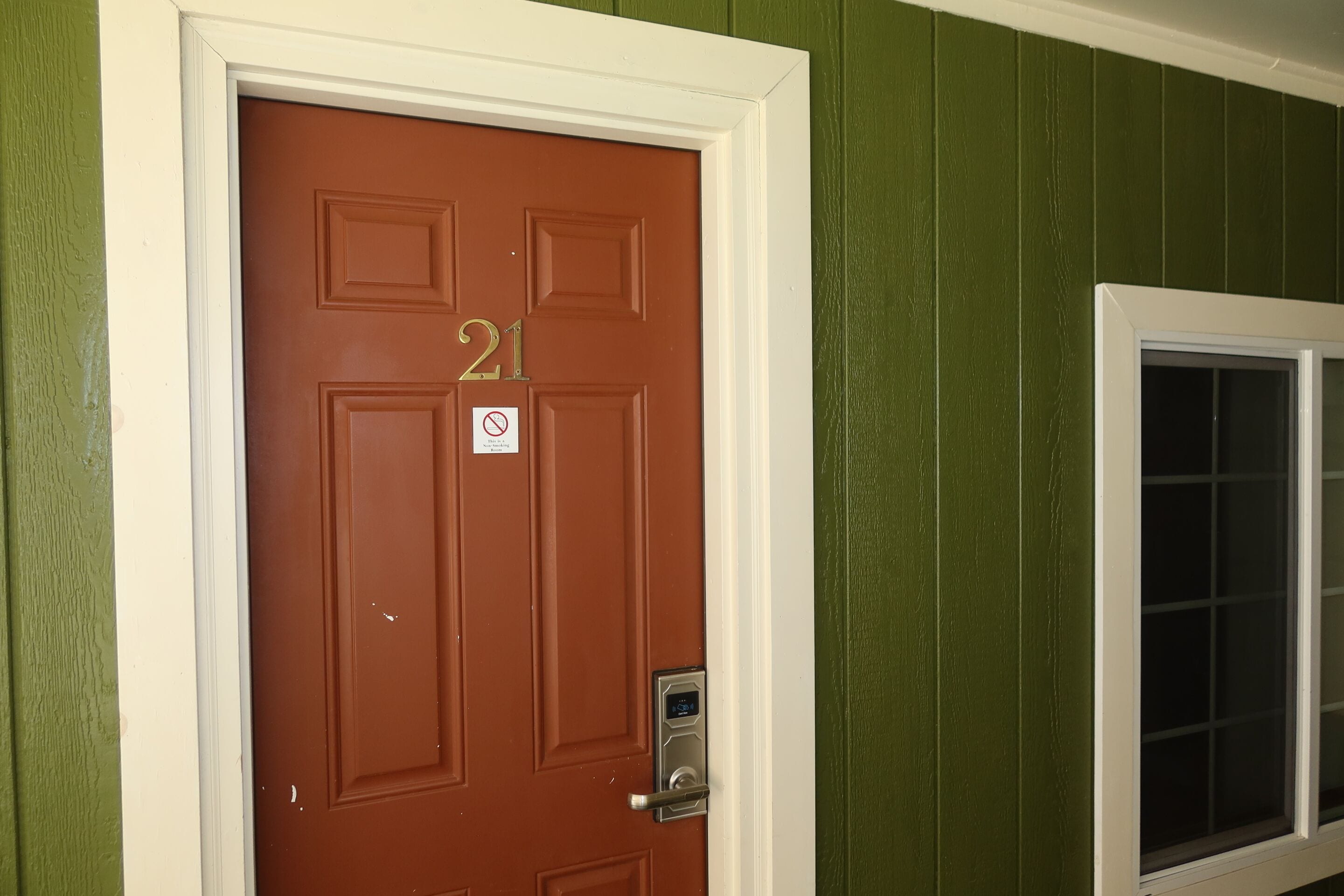 A brown door with the number 21, a no smoking sign, and a window with a grid pattern.