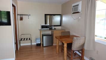 A compact kitchen with a microwave, refrigerator, and a small dining table with chairs.