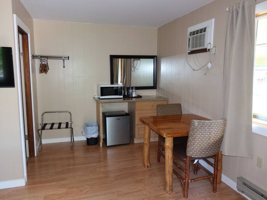 A compact kitchen with a microwave, refrigerator, and a small dining table with chairs.