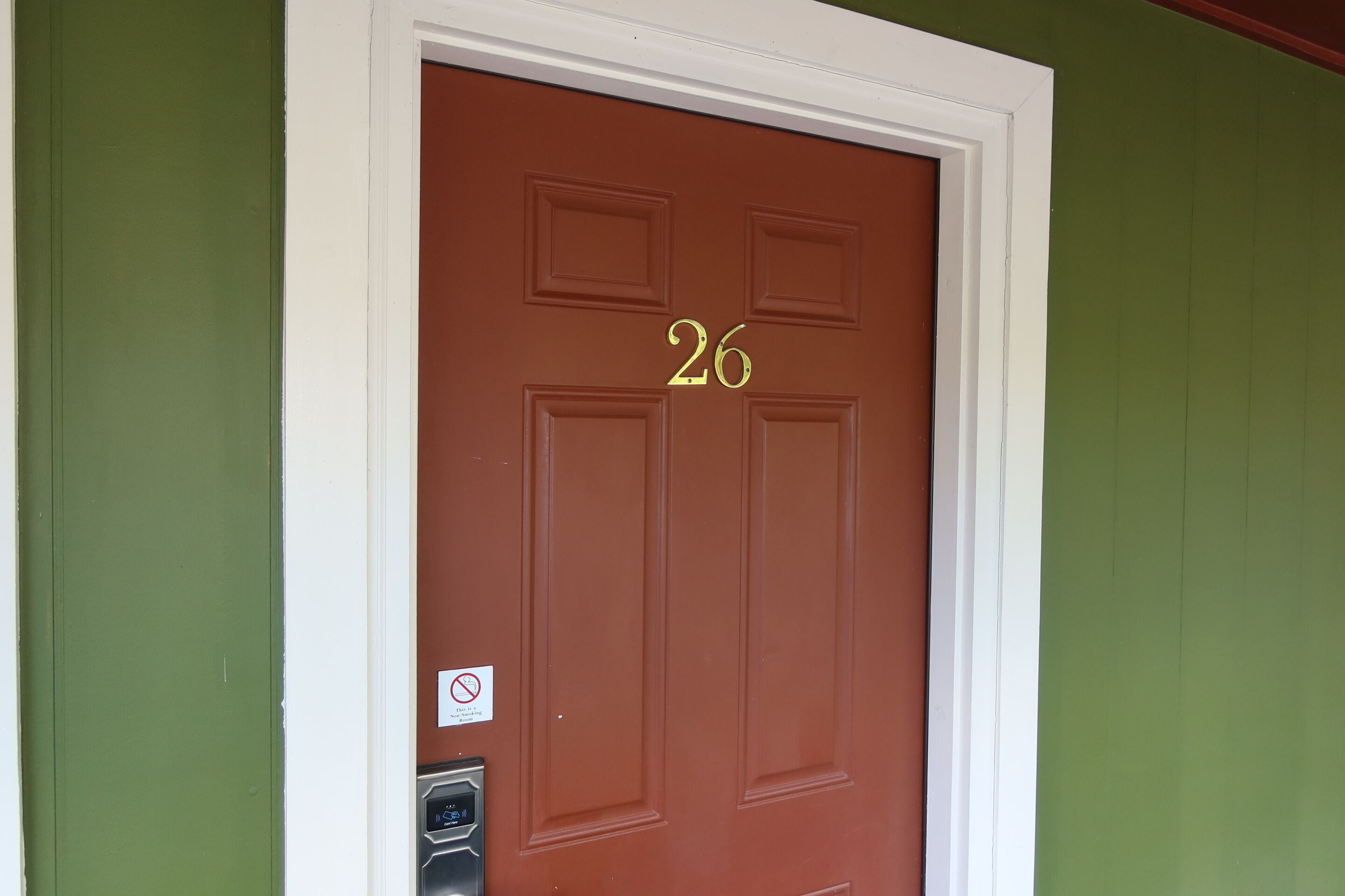 A brown door with the number 26, a doorbell, and a no parking sign.
