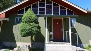A green building with a red door, a small porch, and a large window. - Mountain View Lodge (Packwood)