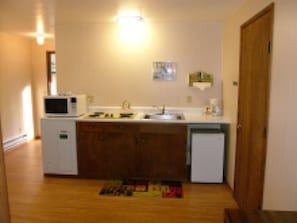 A compact kitchen with a microwave, sink, and cabinets. - Mountain View Lodge (Packwood)