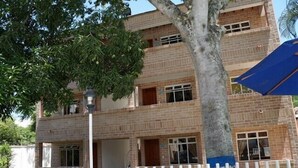 A multi-story building with a brick facade, a white picket fence, and a tree in the foreground. - Hostería Fundadores (Santa Fe de Antioquia)