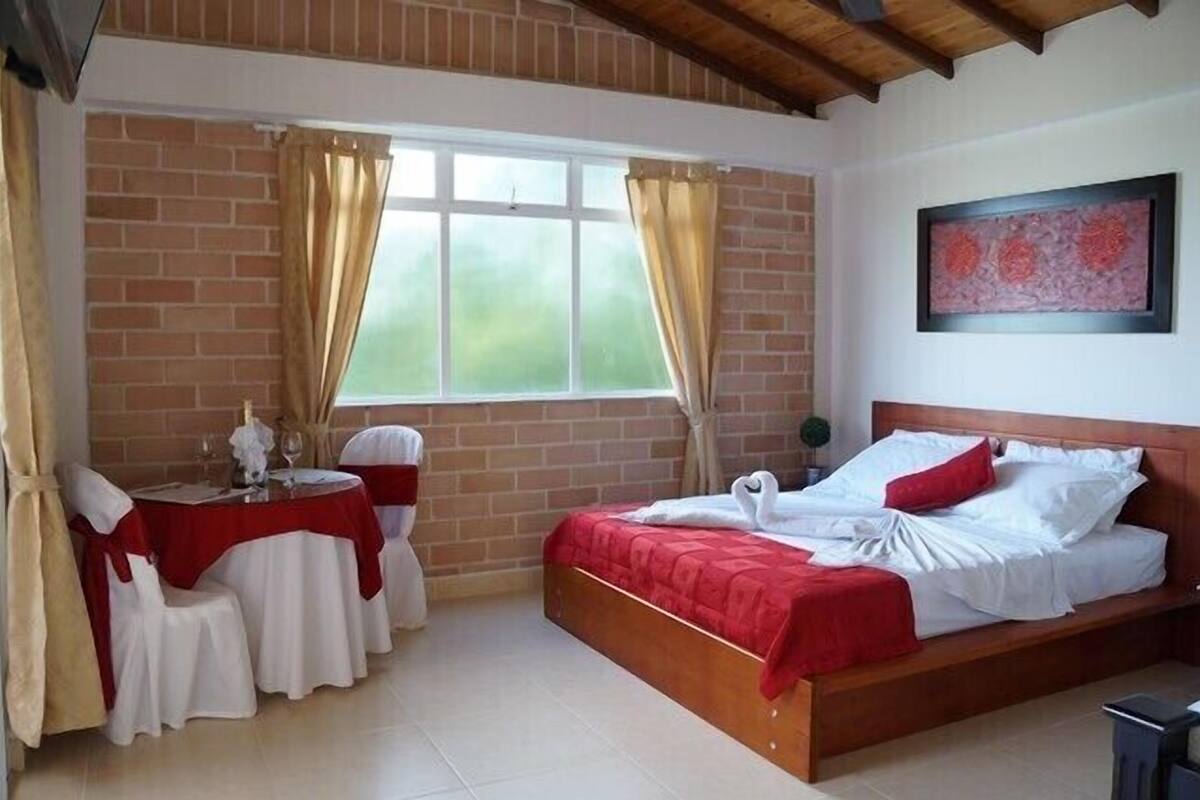 Una camera da letto con un letto di legno, un tavolino rotondo con sedie e una finestra con tende.