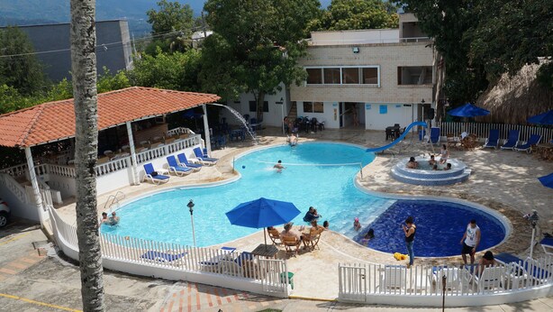 A swimming pool area with multiple pools, lounge chairs, and umbrellas. - Hostería Fundadores (Santa Fe de Antioquia)