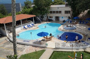 A swimming pool area with multiple pools, lounge chairs, and umbrellas. - Hostería Fundadores (Santa Fe de Antioquia)