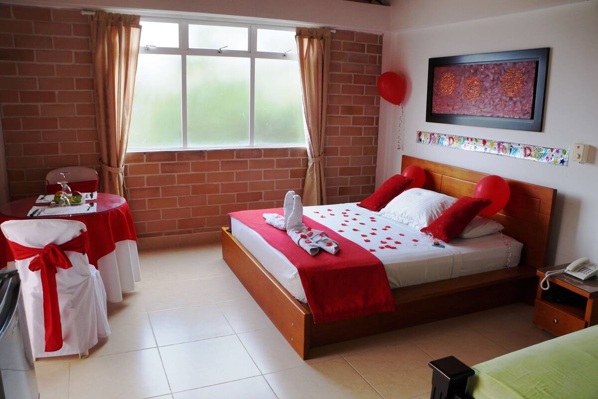 Una camera d'albergo con un letto, un comodino, una sedia, una finestra e un elemento decorativo al muro.