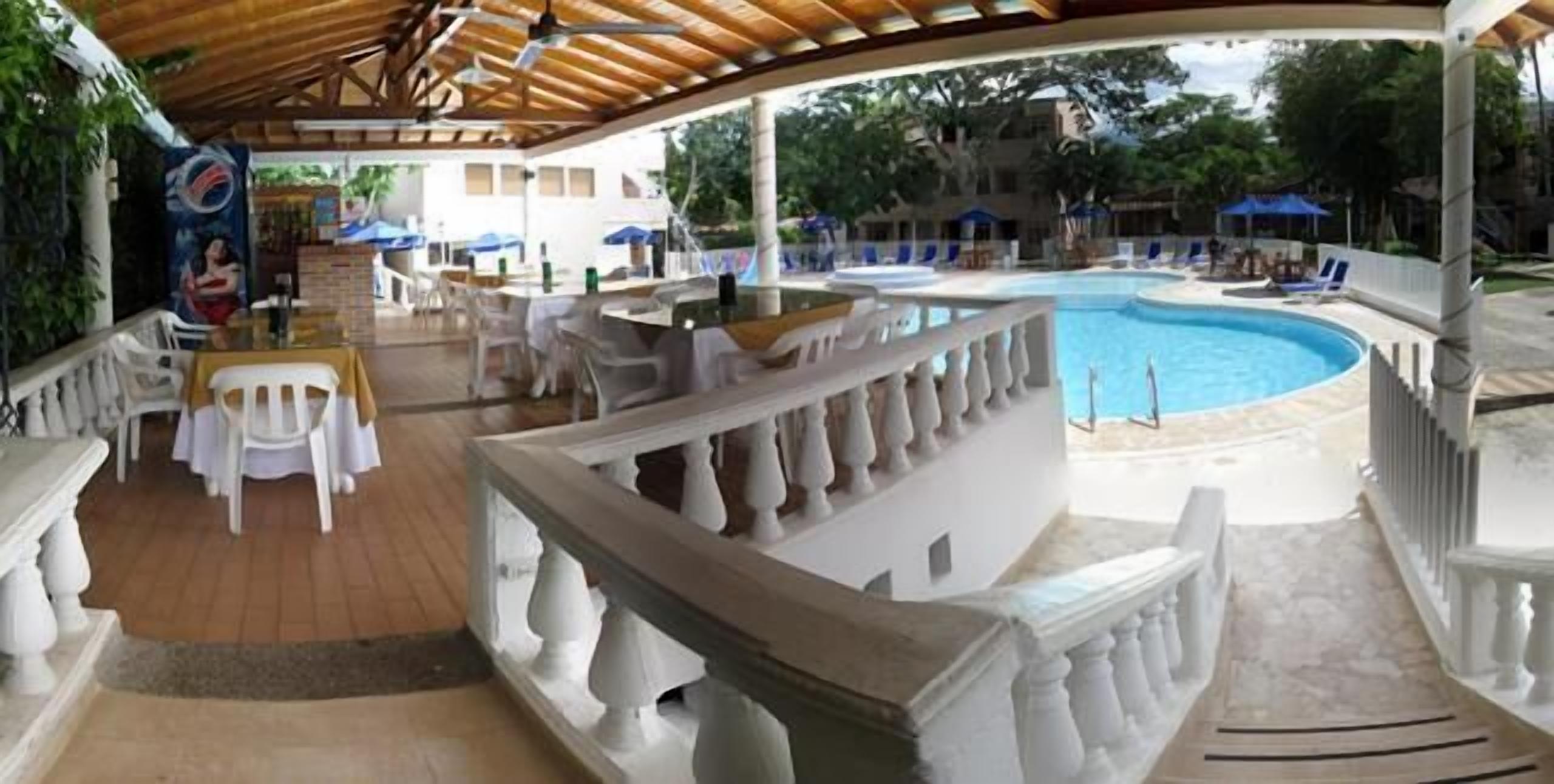 A covered outdoor area with a pool, white outdoor furniture, and a bar area.