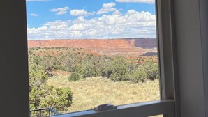 A view of a red rock canyon with sparse vegetation and a clear blue sky.