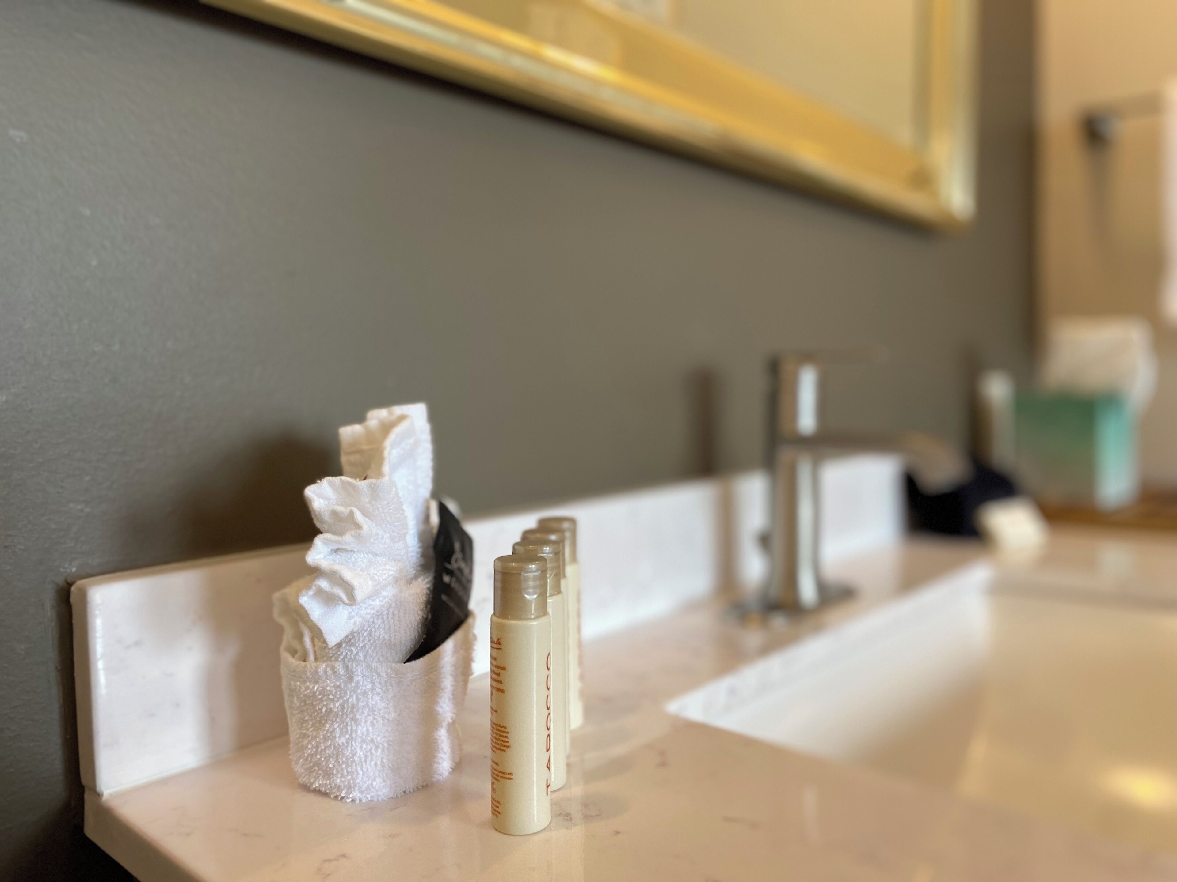 A bathroom sink with a towel holder containing a folded towel and a bottle of lotion.