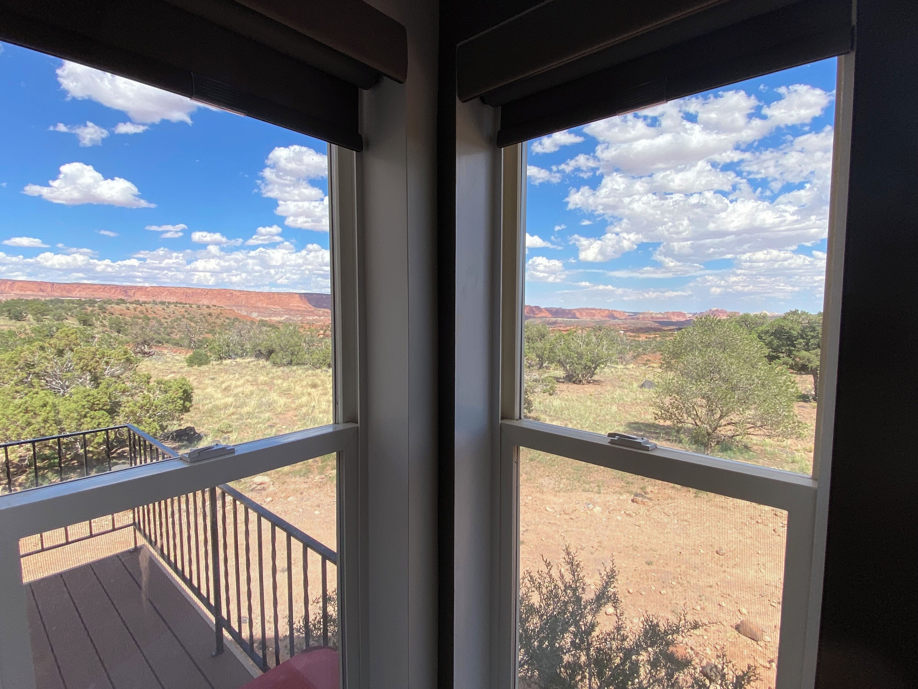A room with a large window overlooking a scenic landscape with red rock formations and sparse vegetation.