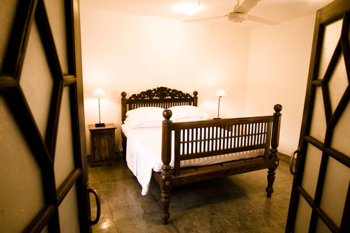 A bedroom with a wooden bed, two bedside lamps, and a ceiling fan.