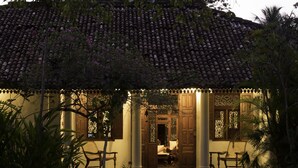 A traditional building with a tiled roof, wooden columns, and a porch with seating. - Nisala Arana Boutique Hotel (Bentota)
