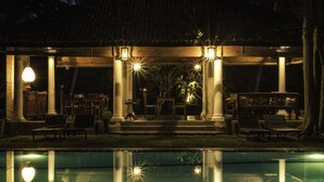 A poolside area with a covered seating area, columns, and a reflection in the water. - Nisala Arana Boutique Hotel (Bentota)